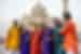 Travellers in opulent colourful garments smile and laugh happily together outside the Taj Mahal at sunset