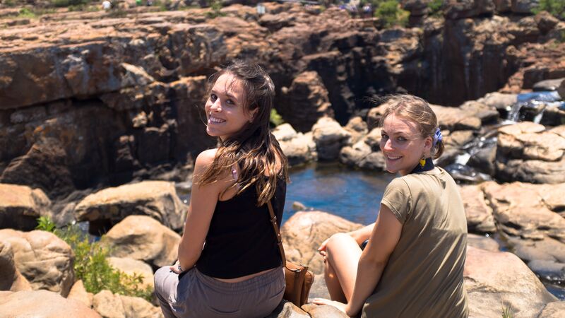 Twee meisjes zitten aan de rand van een ravijn in Zuid-Afrika. 