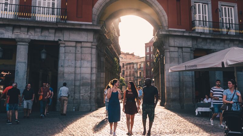 Three people walking through a square in Madrid at sunset