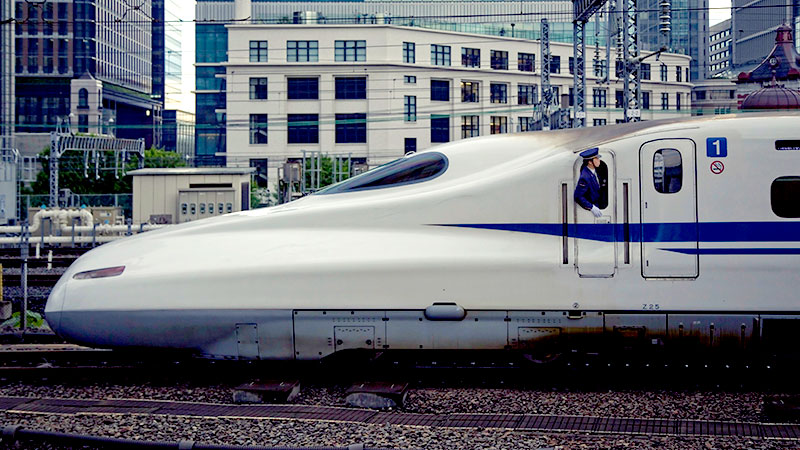 Bullet train in the middle of a Japanese city with driver looking out from the window