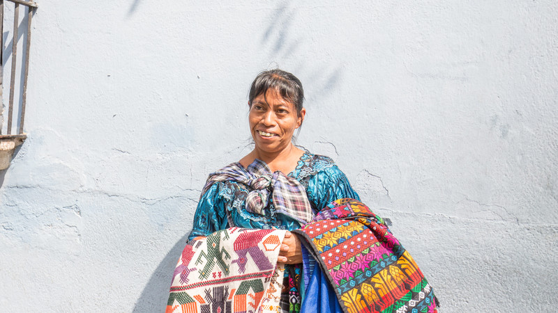 Guatemalan woman holding bright coloured textiles