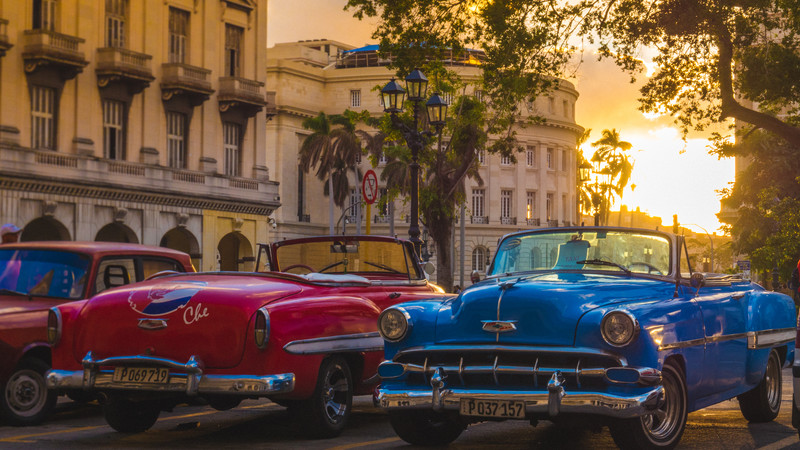 Three vintage cars parked on a street at sunset in Havana, Cuba