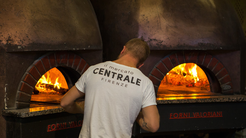 Man in front of a hot pizza oven