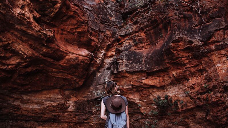 A traveller looking up at a huge rock in Australia