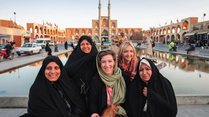 Two travellers with a group of smiling Iranian women