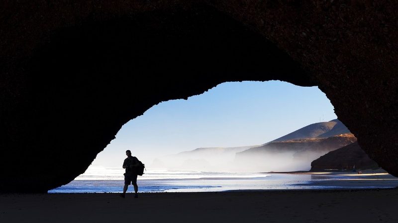 Person standing under a stone archway.