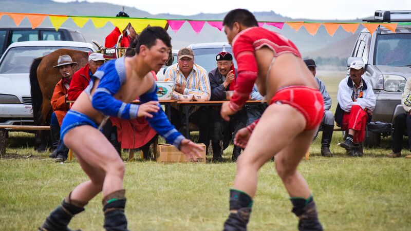 Two people wrestling in Mongolia at Naadam Festival