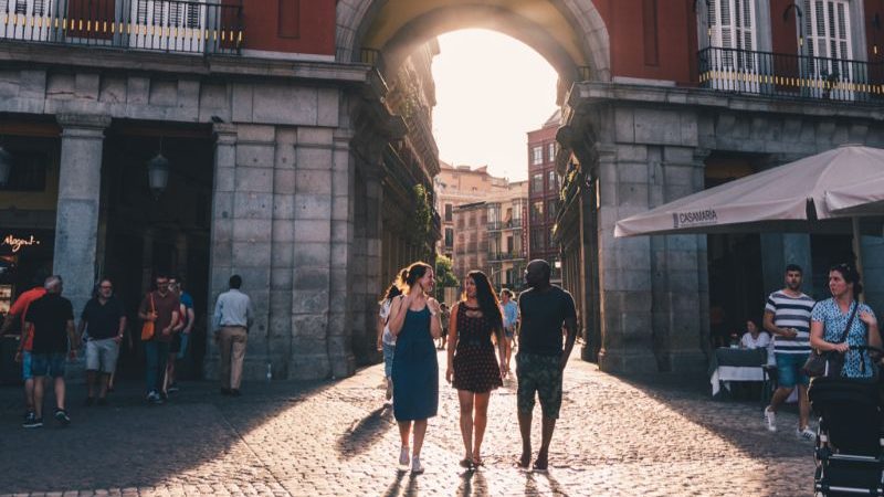 Three people walking into a square in Madrid at sunset