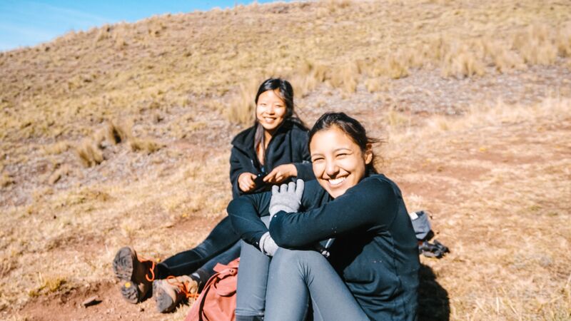 Two girls sitting in a field in Peru