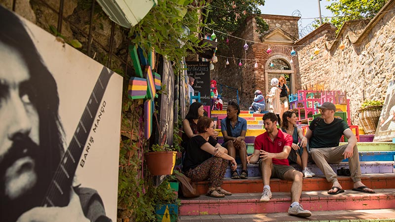 Travellers sitting on colourful steps outside a cafe in Istanbul