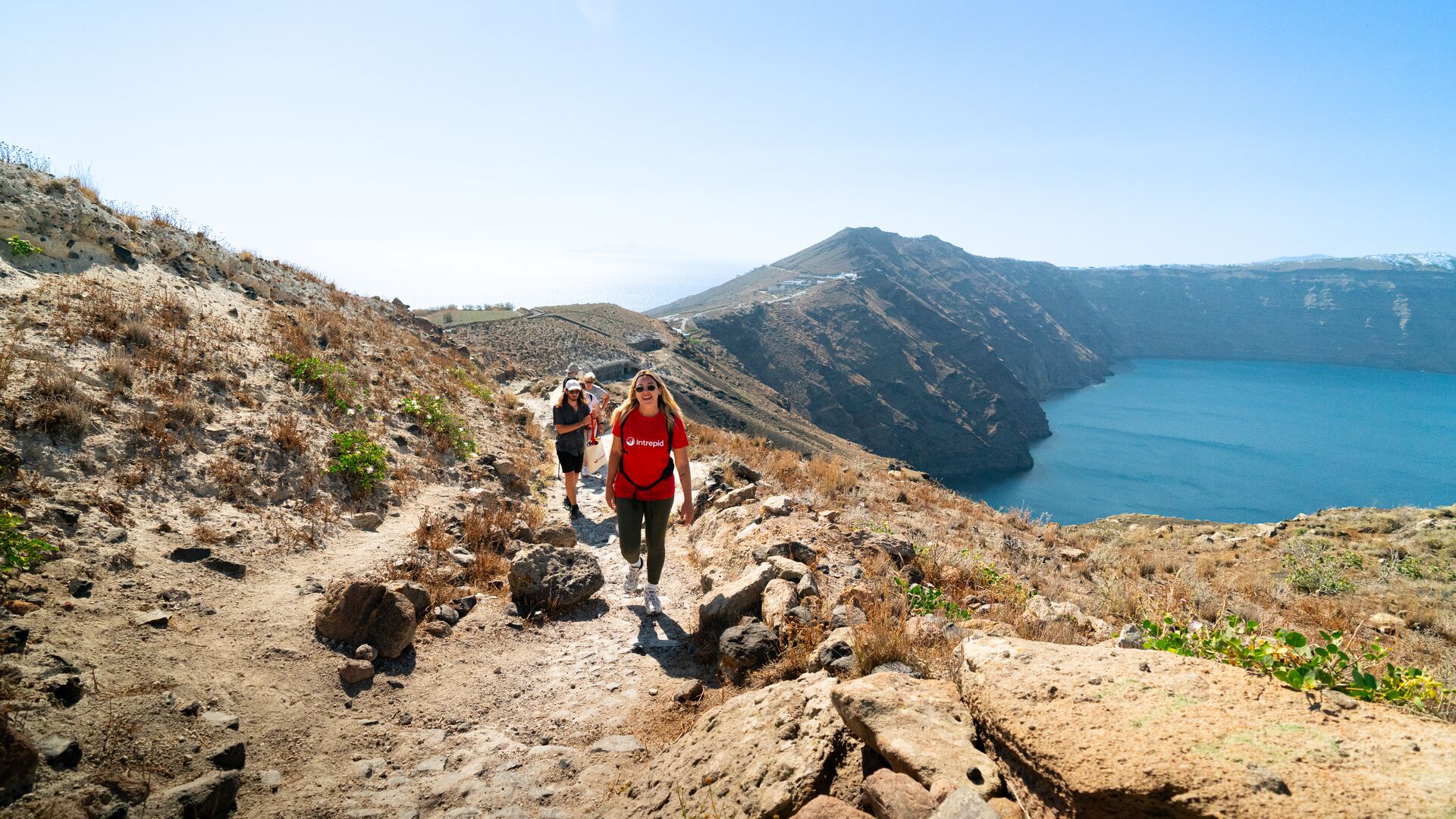 A group of Intrepid travellers hiking around a volcanic crater in Santorini, Greece