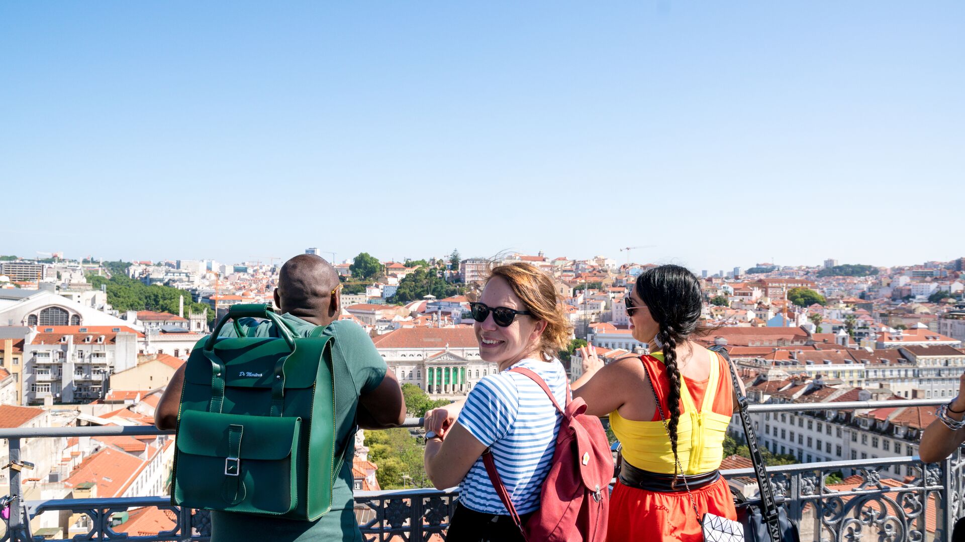 Three travellers admiring the view of Lisbon from a rooftop