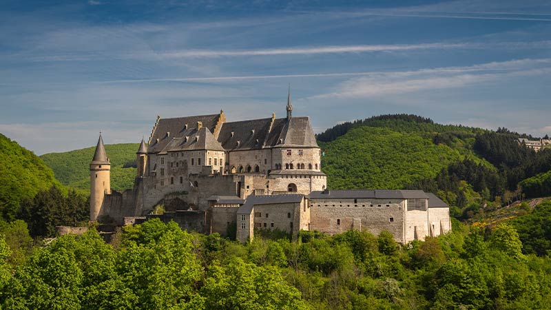 The picturesque structure of Vianden Castle surrounded by lush vegetation.  