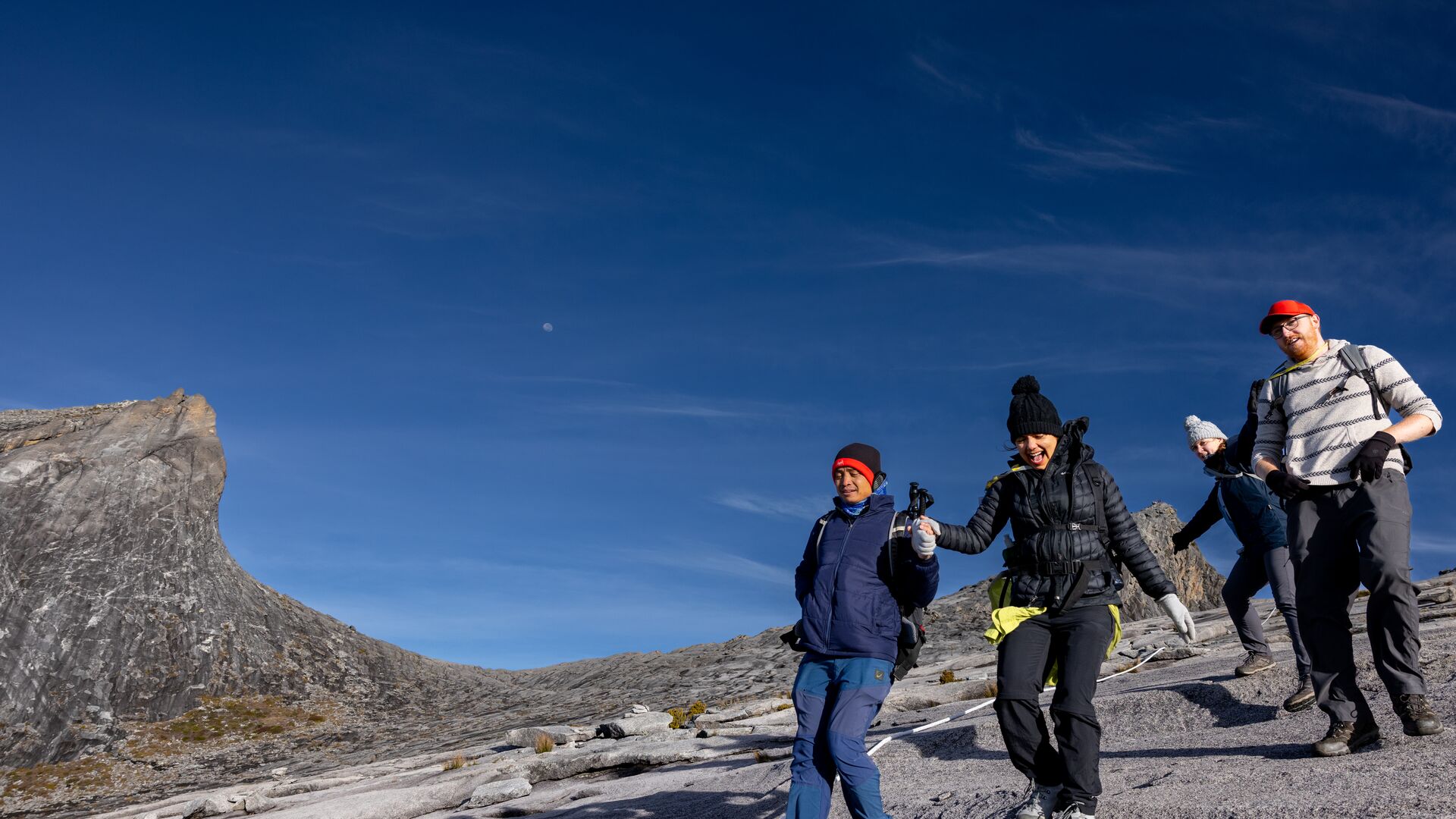 Three travellers and a mountain guide descending Low's Peak after summiting Mt Kinabalu