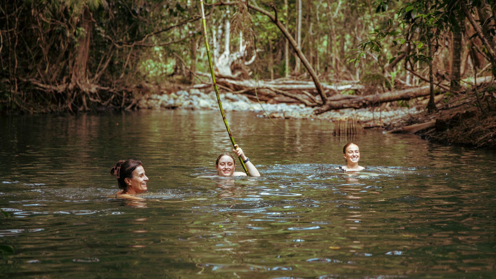 Three travellers swimming in a a waterhole in Cape Tribulation in Queensland, Australia