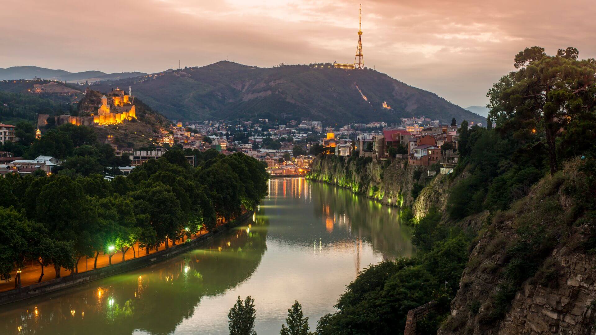 A panoramic shot of Tbilisi as the sun sets and the lights reflect off the water