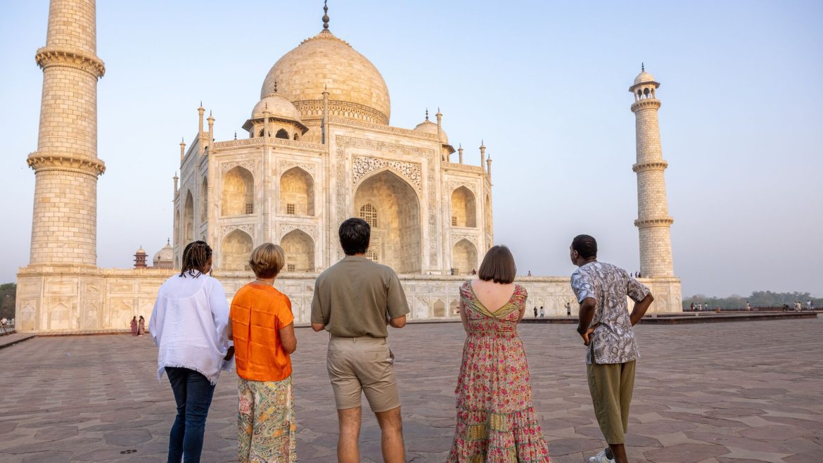 Five travellers admiring the Taj Mahal at sunrise