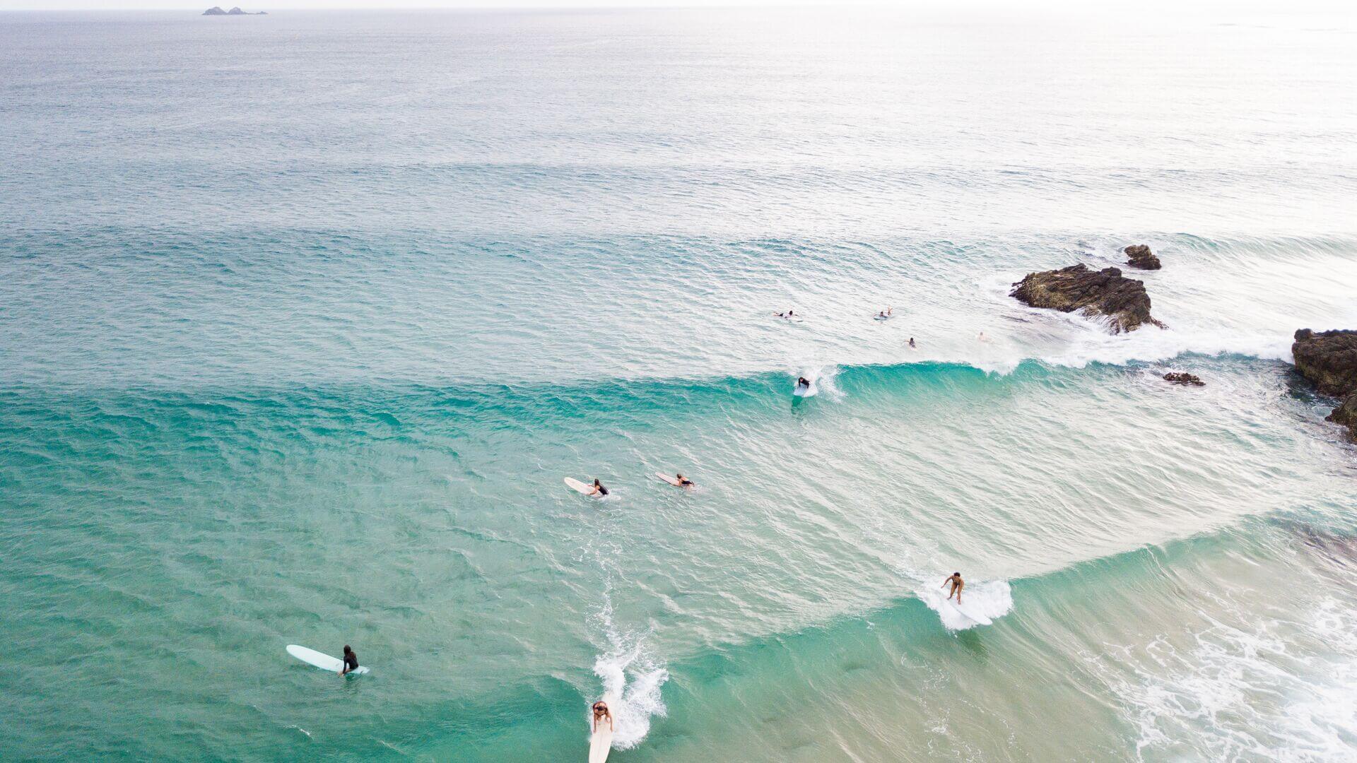 Surfers surfing in clear blue waters of Byron Bay, Australia