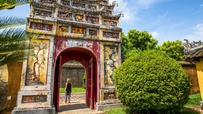 Woman walking underneath a traditional citadel in Hue, Vietnam