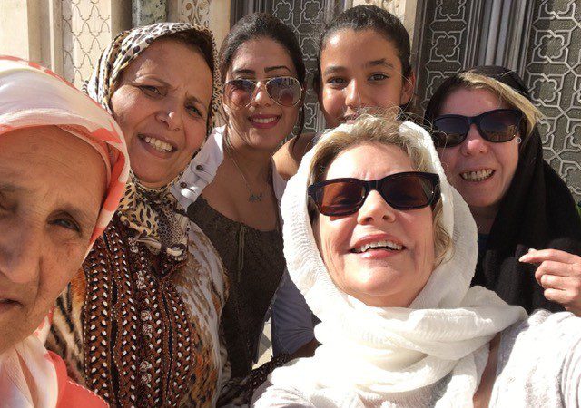 Four Moroccan women and two female travellers pose for a selfie in the sunshire