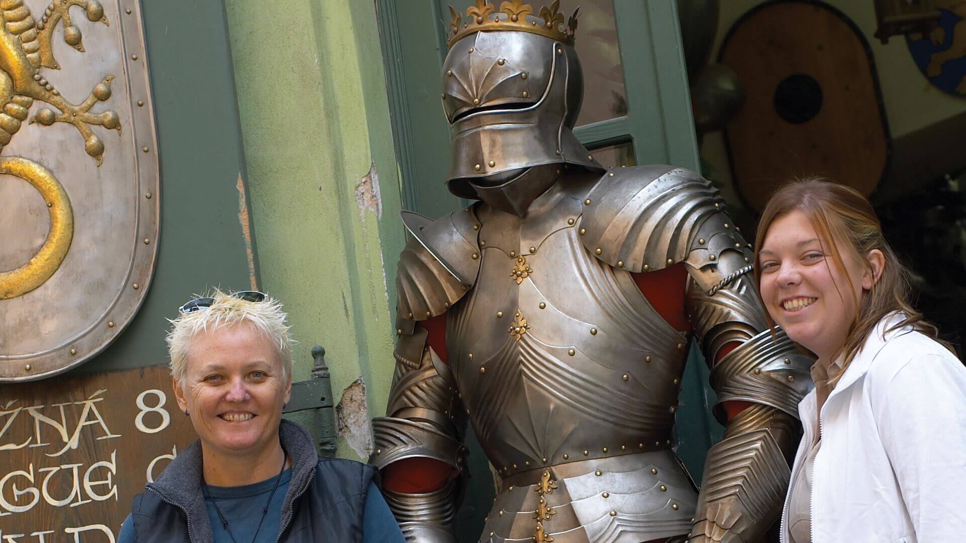 Travellers pose with a medieval suit of armour in Prague