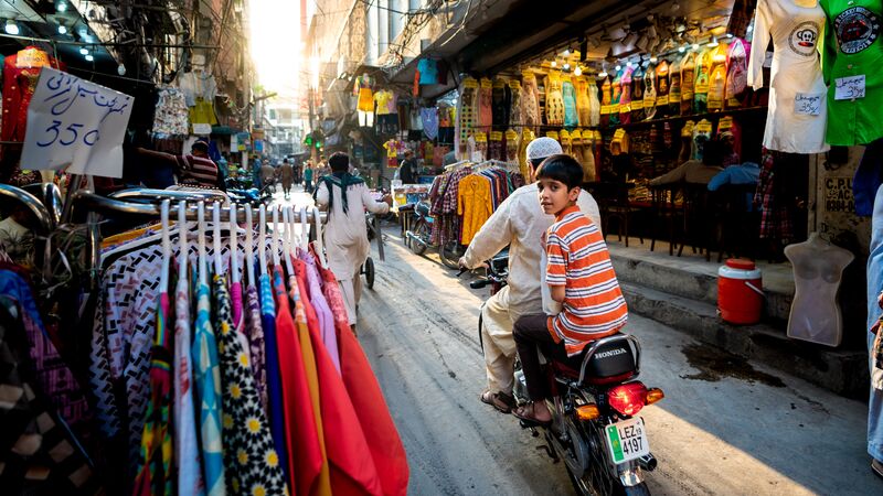 A local boy riding on the back of a scooter through Anarkali Bazaar in Lahore, Pakistan