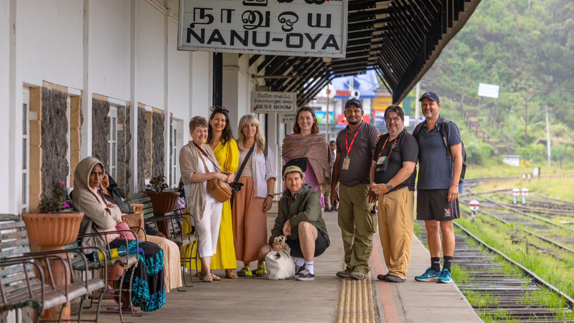 A group of smiling travellers at a train station in Sri Lanka.