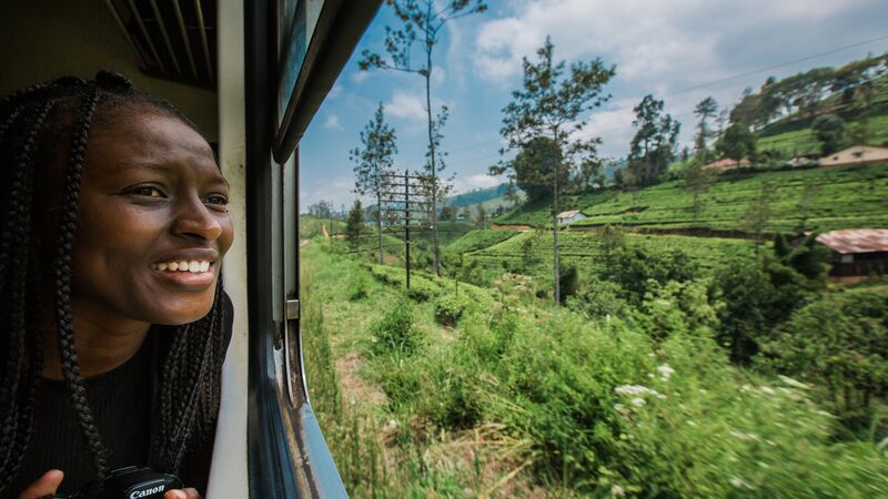 A travellers look out of the window of a moving train at the lush landscapes of Sri Lanka.