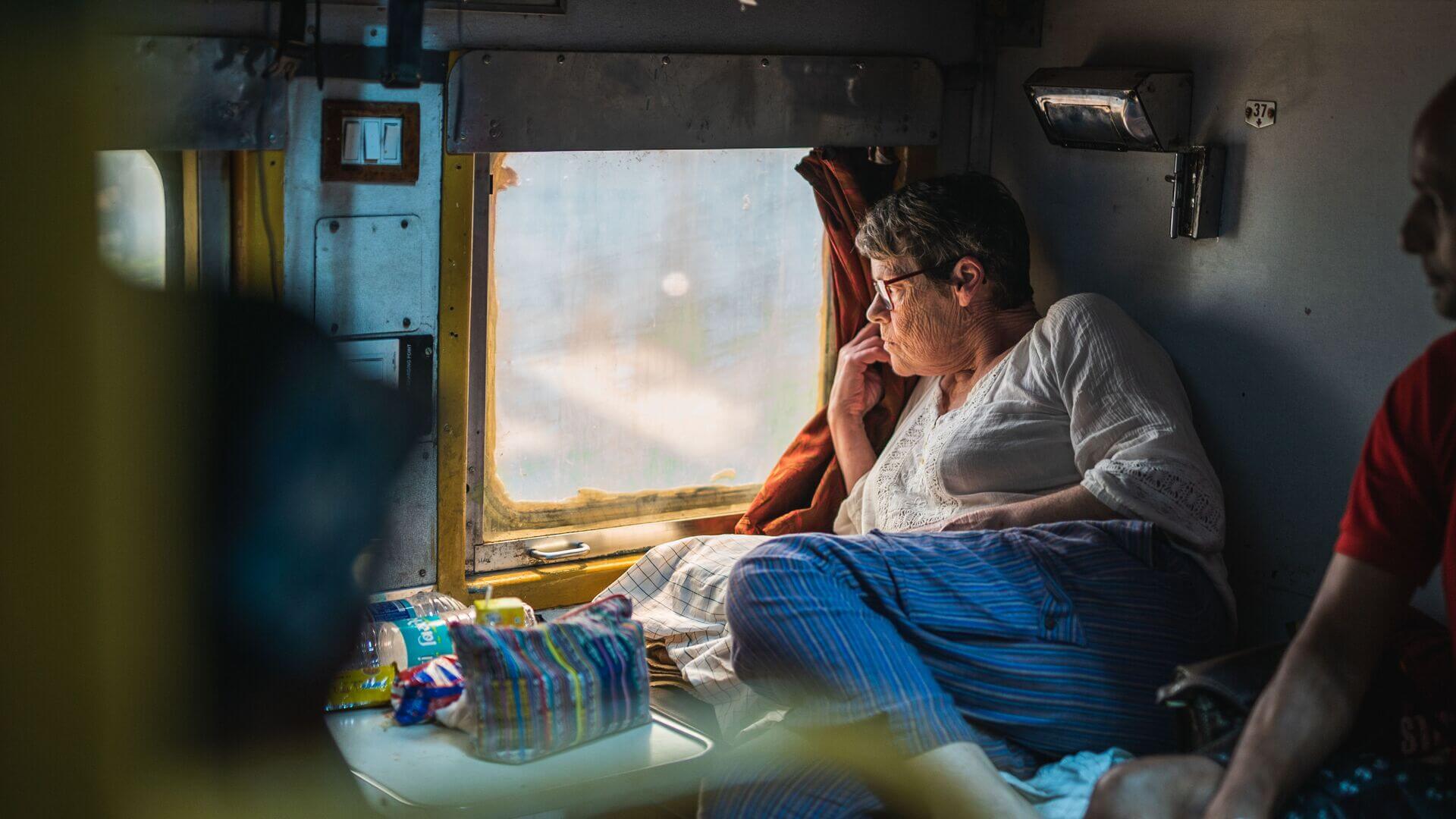 Older woman traveller looking out the window on an Indian sleeper train