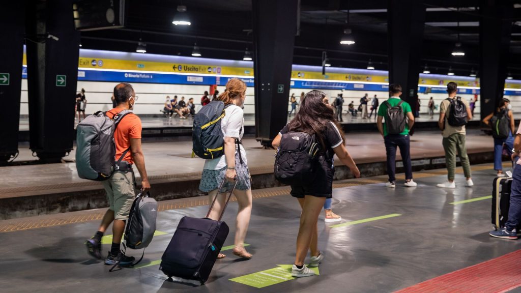 A group of travellers walking along a train platform in Italy