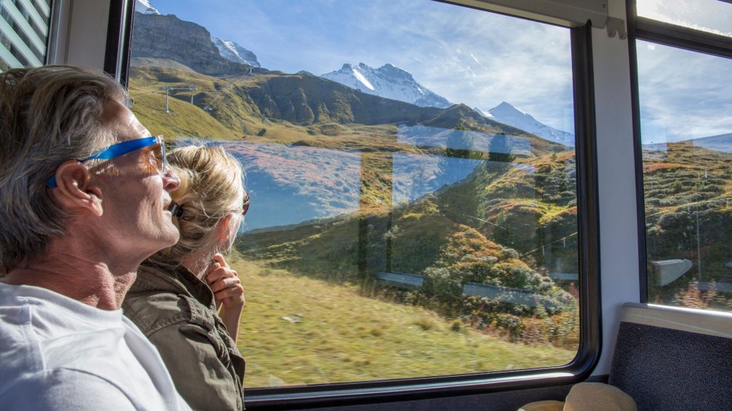 Two travellers gazing out of the window on a train ride in Switzerland