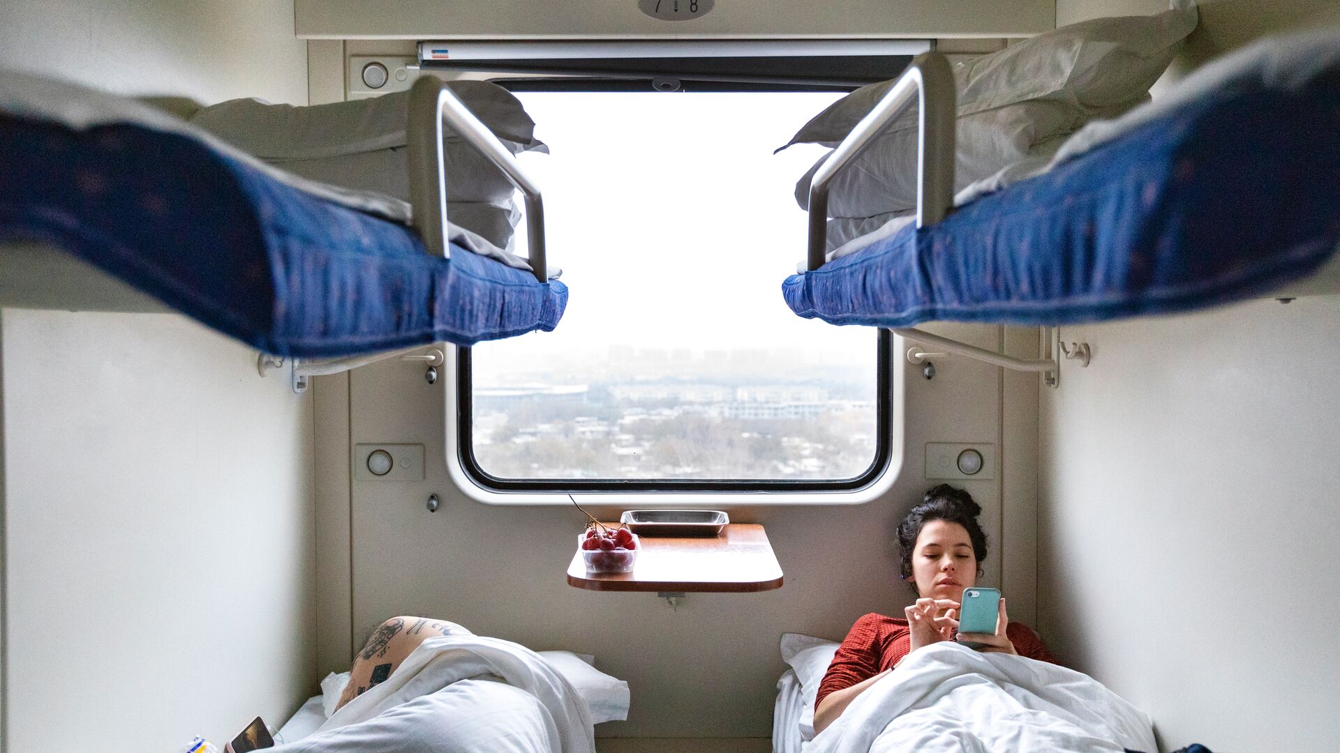 Two travellers relaxing in their compartment on a sleeper train in China