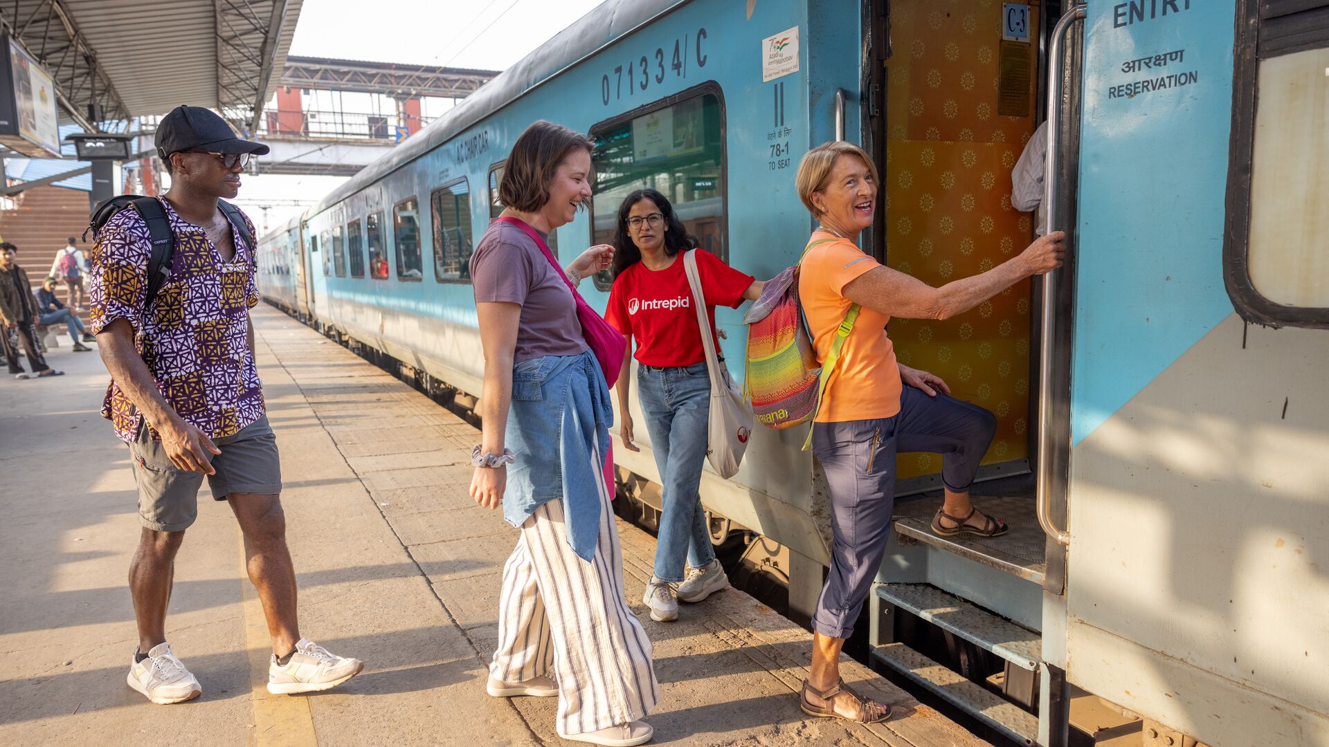 Three travellers and Intrepid leader boarding a train in New Delhi