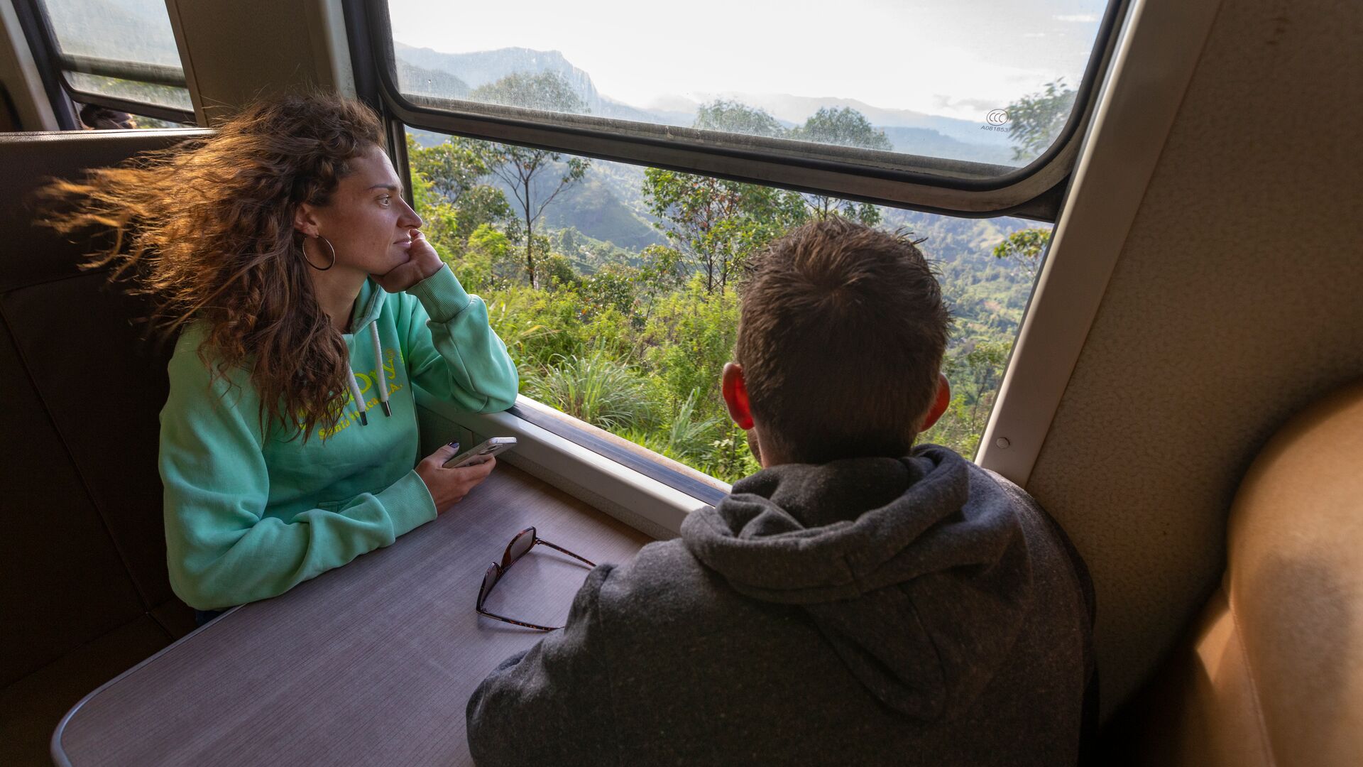 Two travellers gazing out of the window on a train journey through Sri Lanka