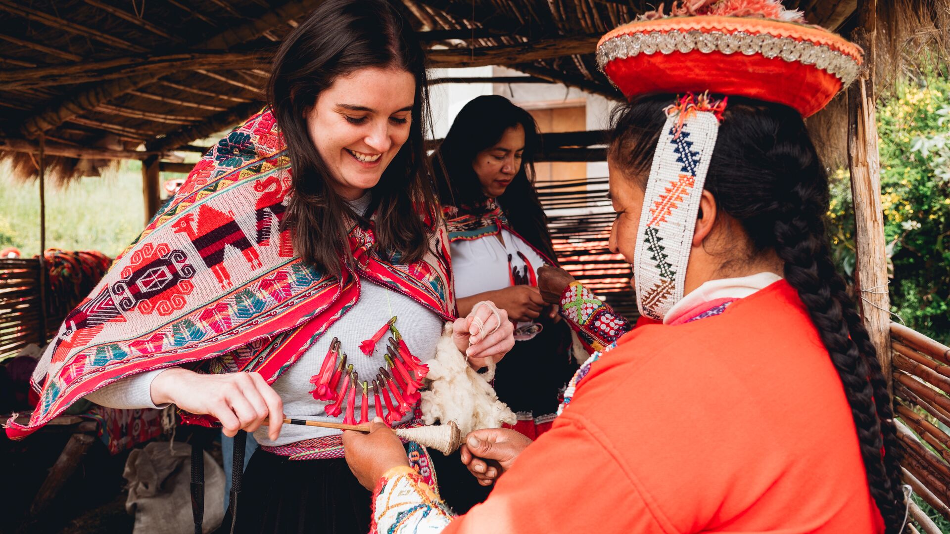 A Huilloc woman from Sacred Valley, Peru dressing a traveller in traditional clothing