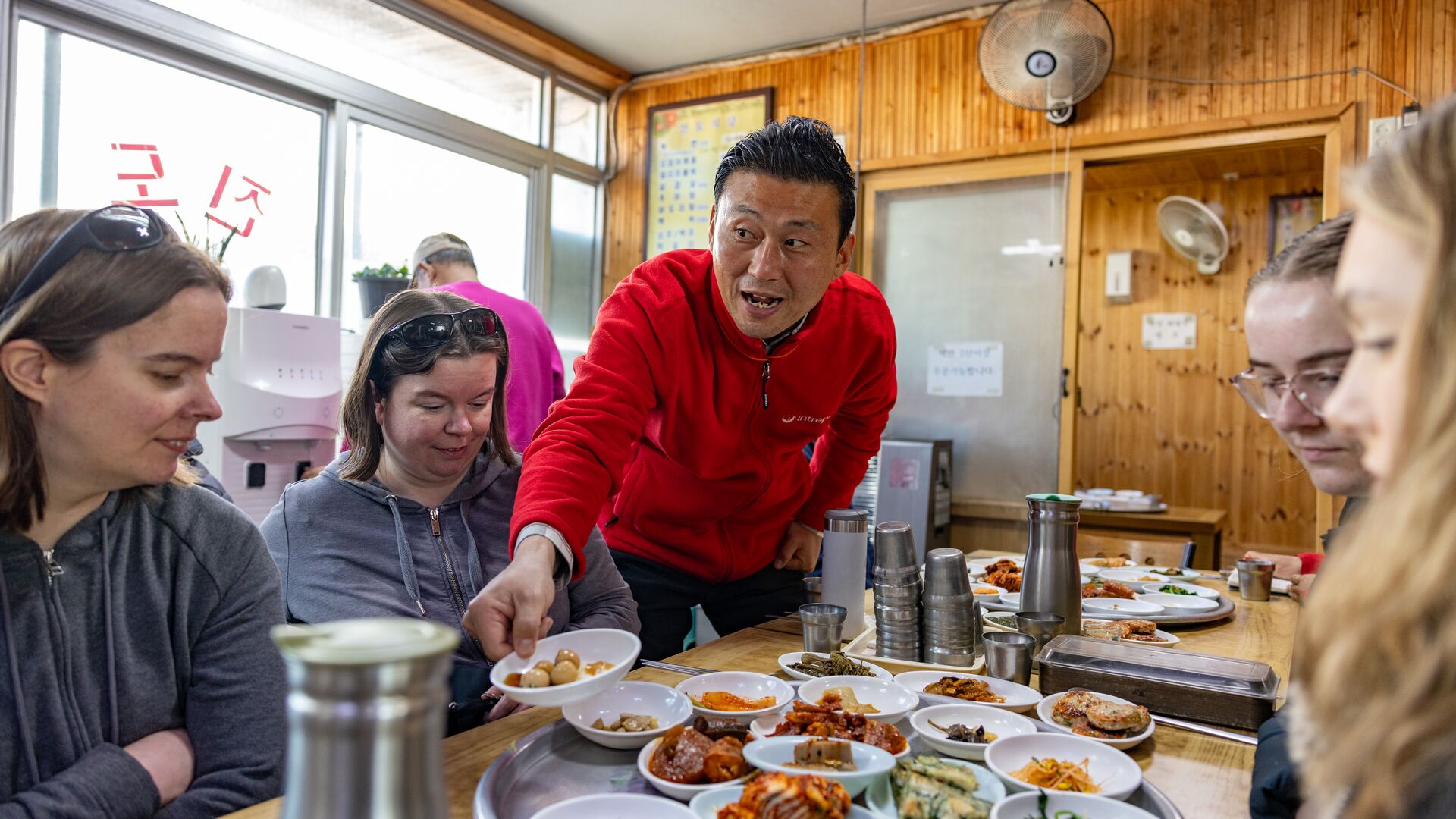 A group of female travellers eating traditional South Korean food with a  local Intrepid leader