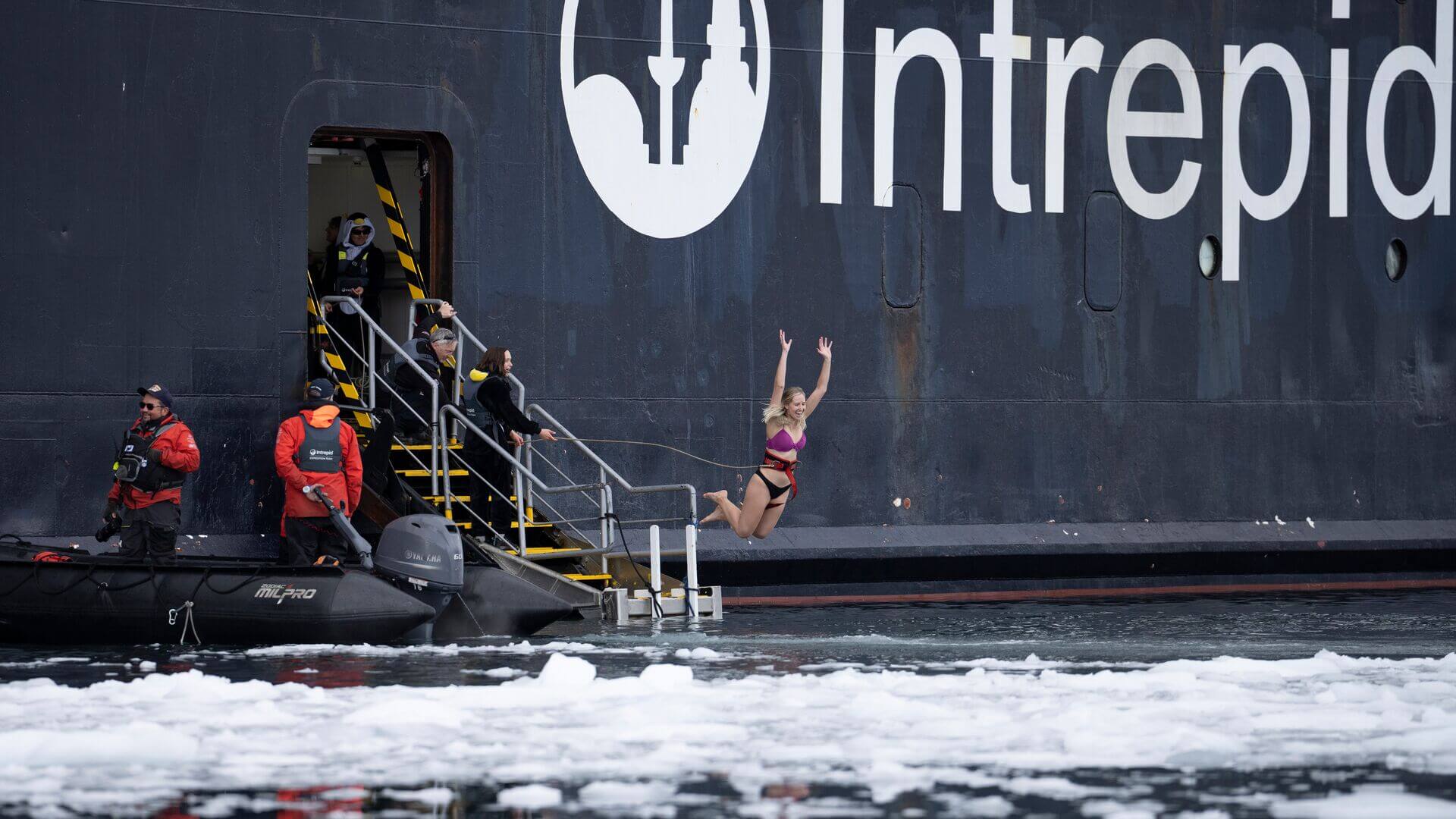 A smiling person mid-jump as they do a polar plunge