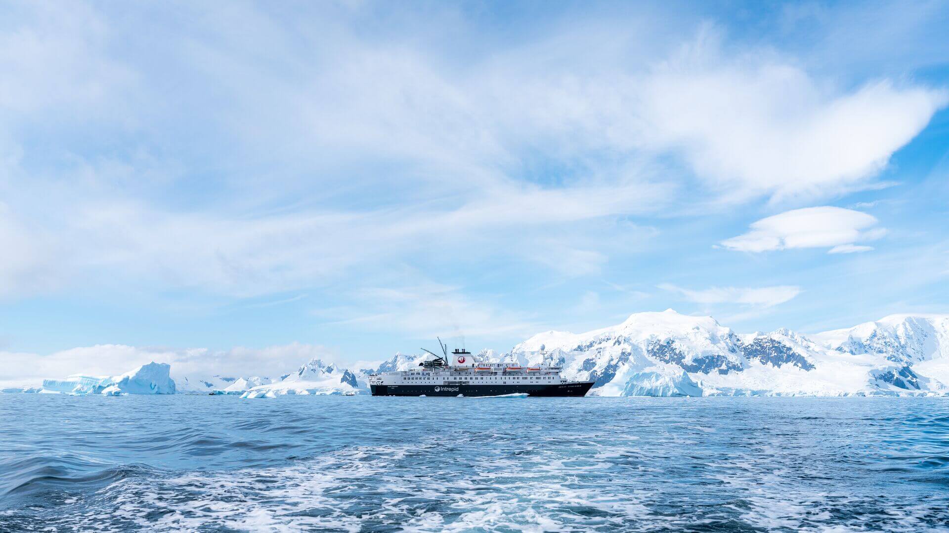 Intrepid ship sailing on icy blue waters around Antarctica