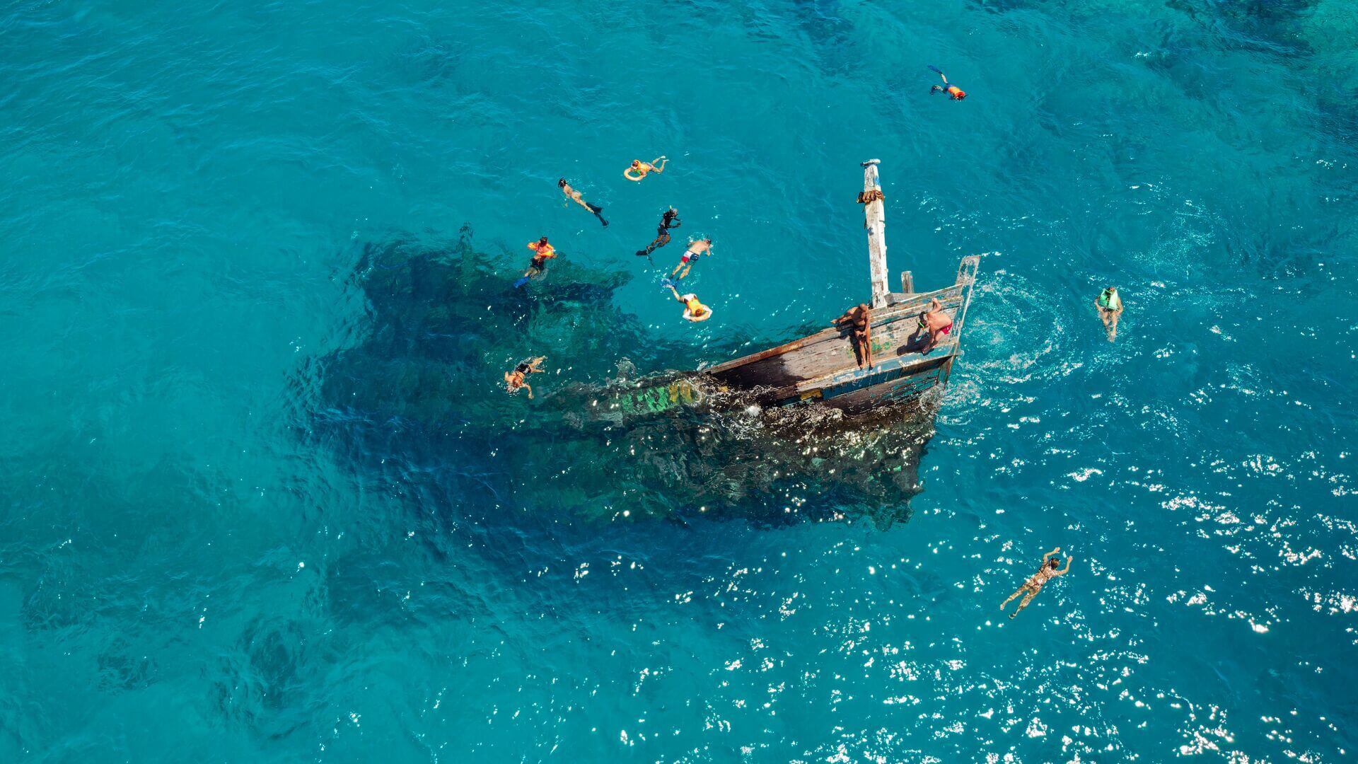 Snorkelers swim around shipwreck in Maldives