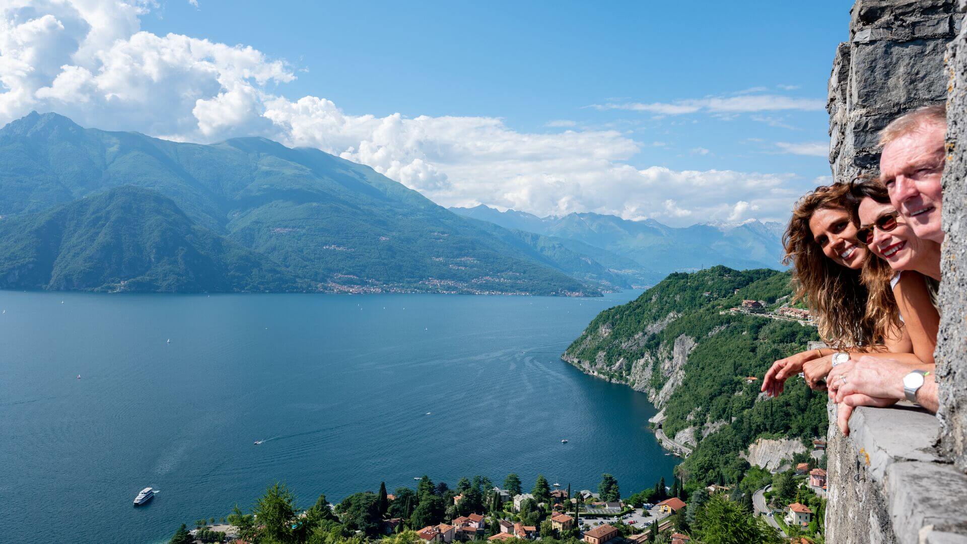 People smile as they look out from castle ruins in Lake Como