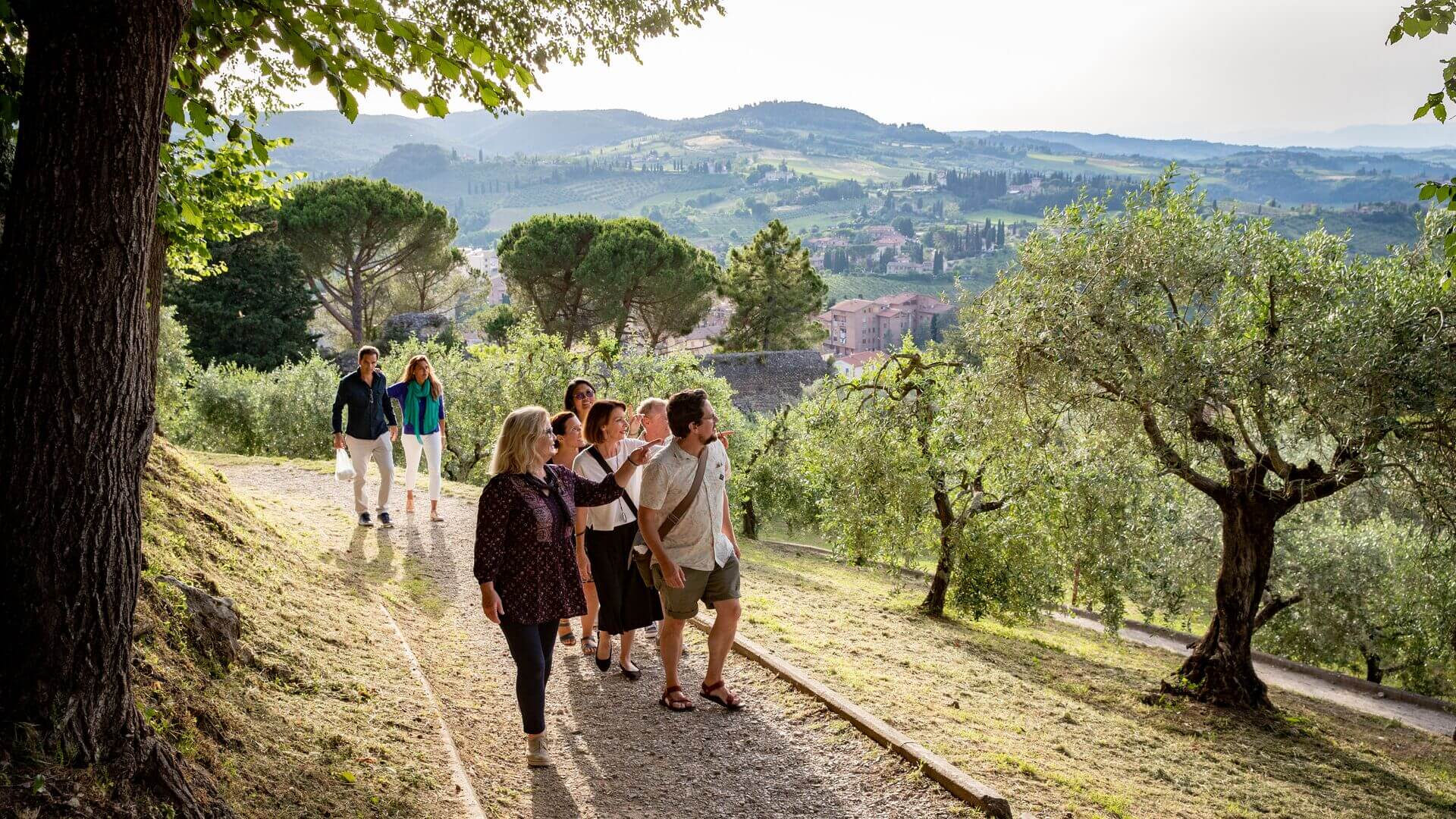 People walk up a path overlooking San Gimignano, Tuscany