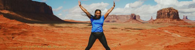 Traveller jumping in the air in Monument Valley in Utah. 