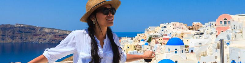  A solo traveler poses in front of Santorini's iconic blue domed church