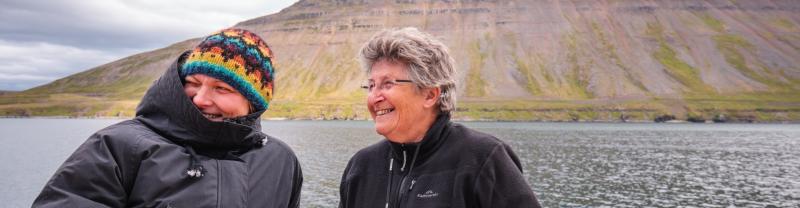 A couple of rugged up travellers looking out at the water of siglufordur in Iceland