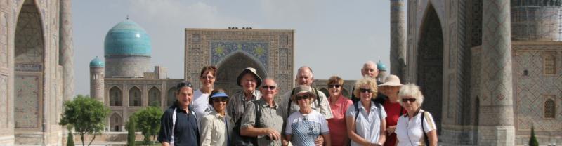 A group of travellers smiling at the camera in Registan Square in Uzbekistan