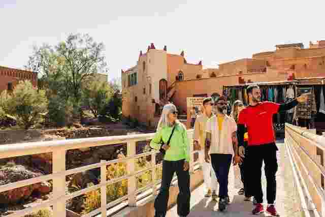 Four Intrepid travelers and a local leader walking over a bridge in Aït Benhaddou, Morocco