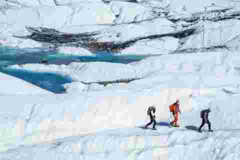 Three hikers walking across Matanuska Glacier in Alaska