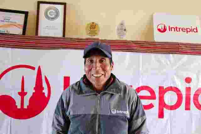 A smiling man standing in front of the Intrepid logo at an office in Peru 