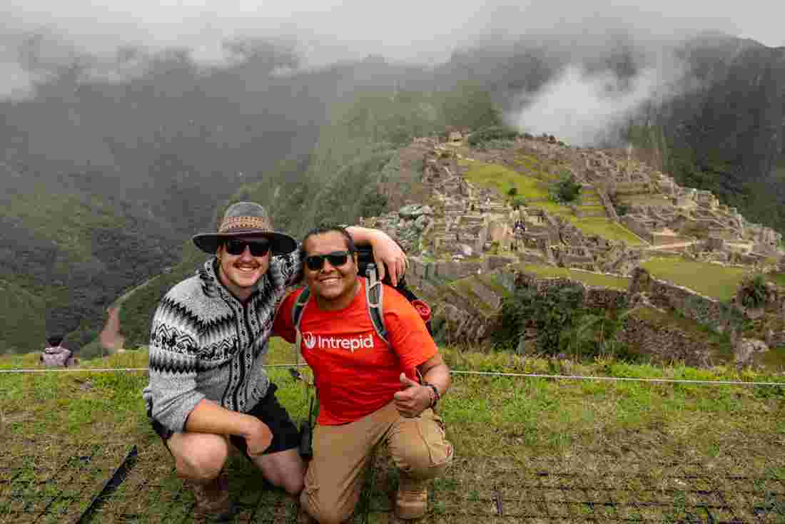 Leader and traveller at summit posing with Machu Picchu in background 