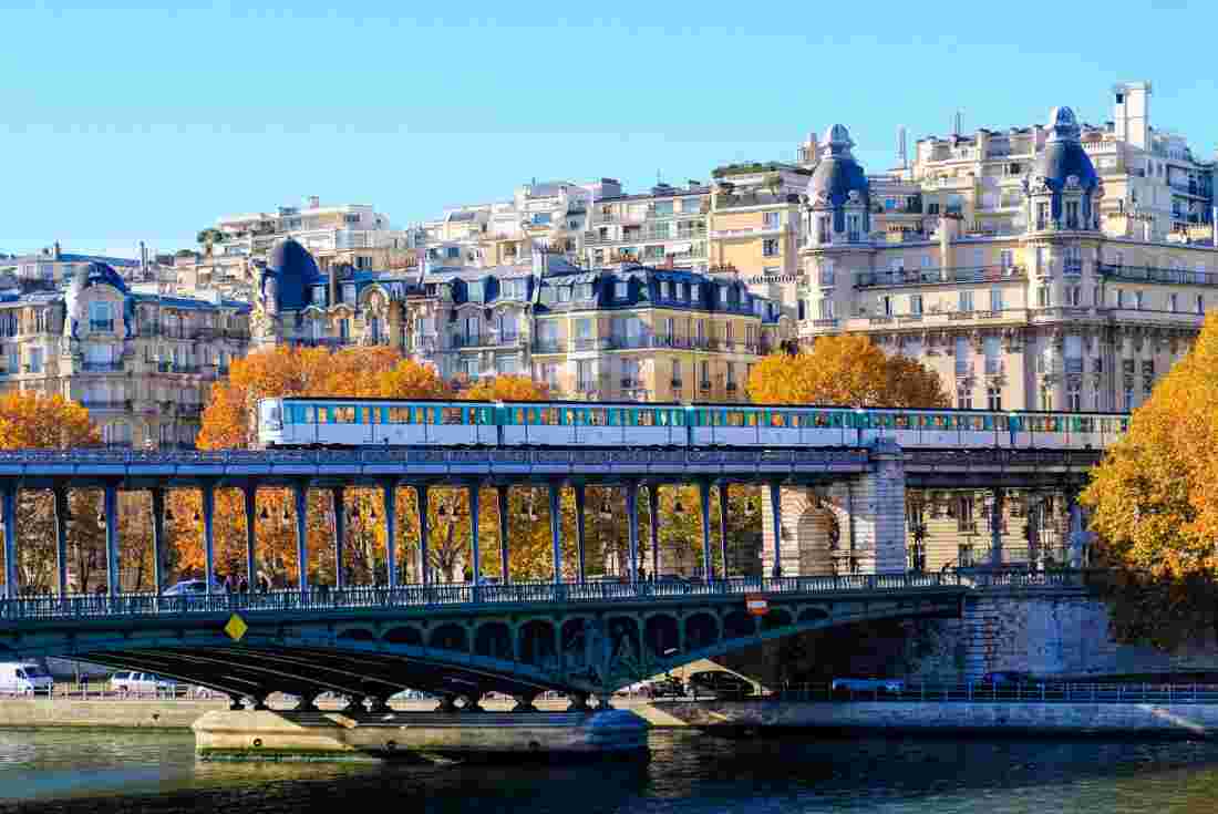 Train over the River Seine in Paris in autumn with classic architecture and bright orange trees